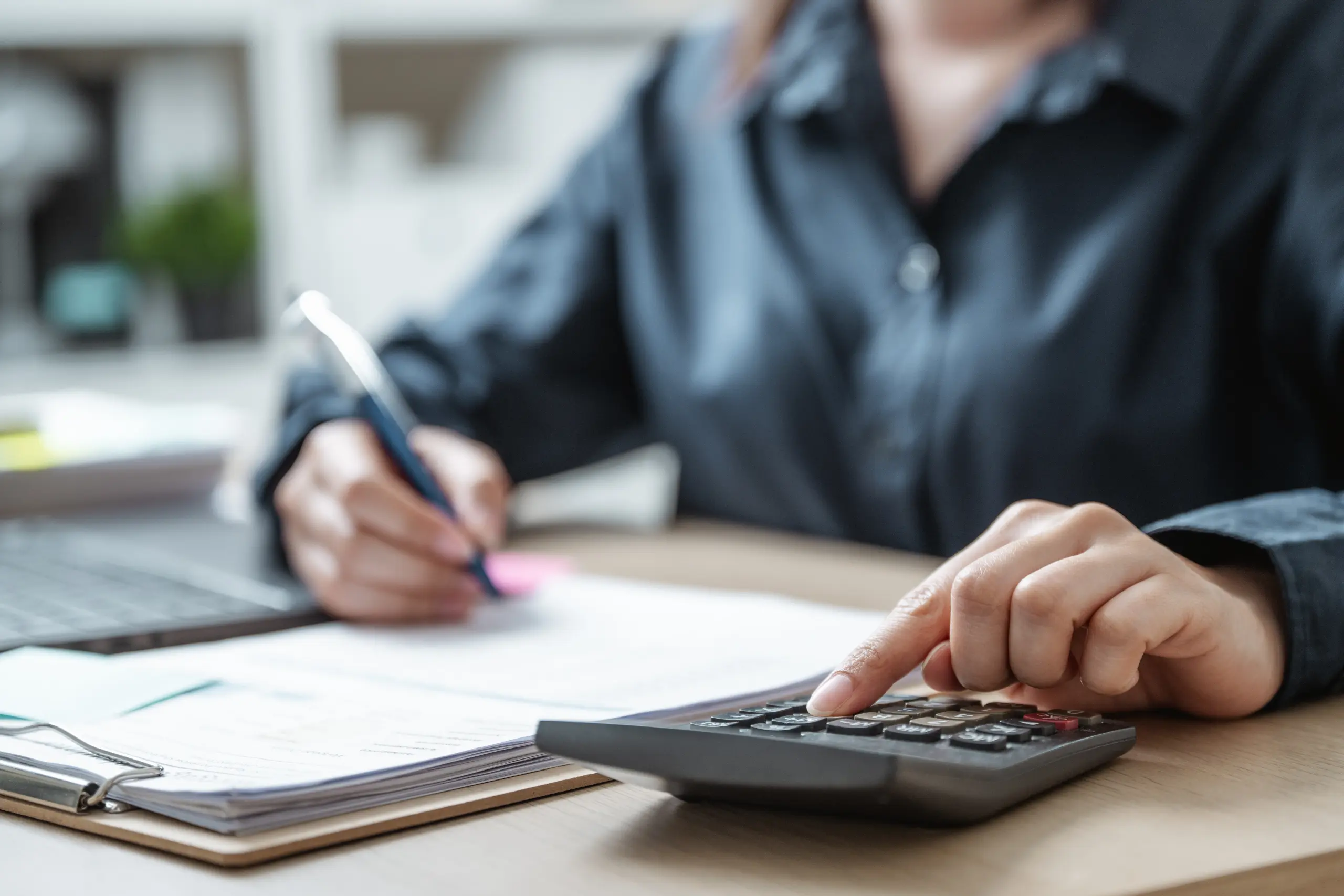 Person using a calculator while reviewing paperwork