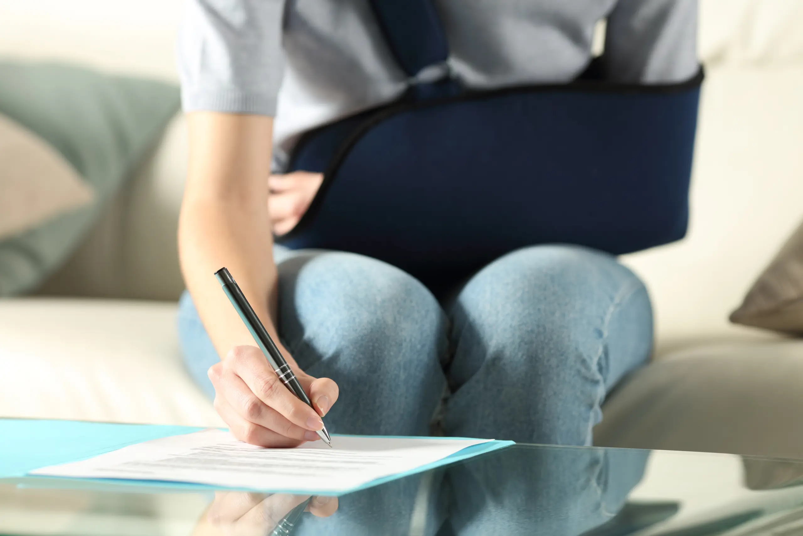 Woman wearing an arm sling signing paperwork