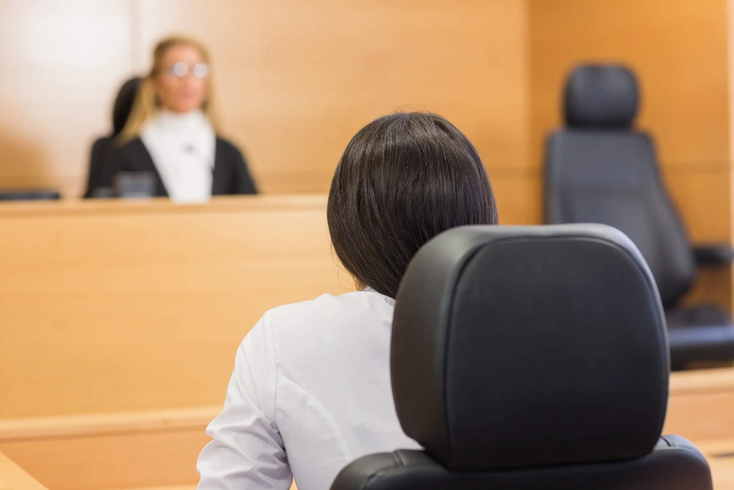 Person seated facing a judge in a courtroom