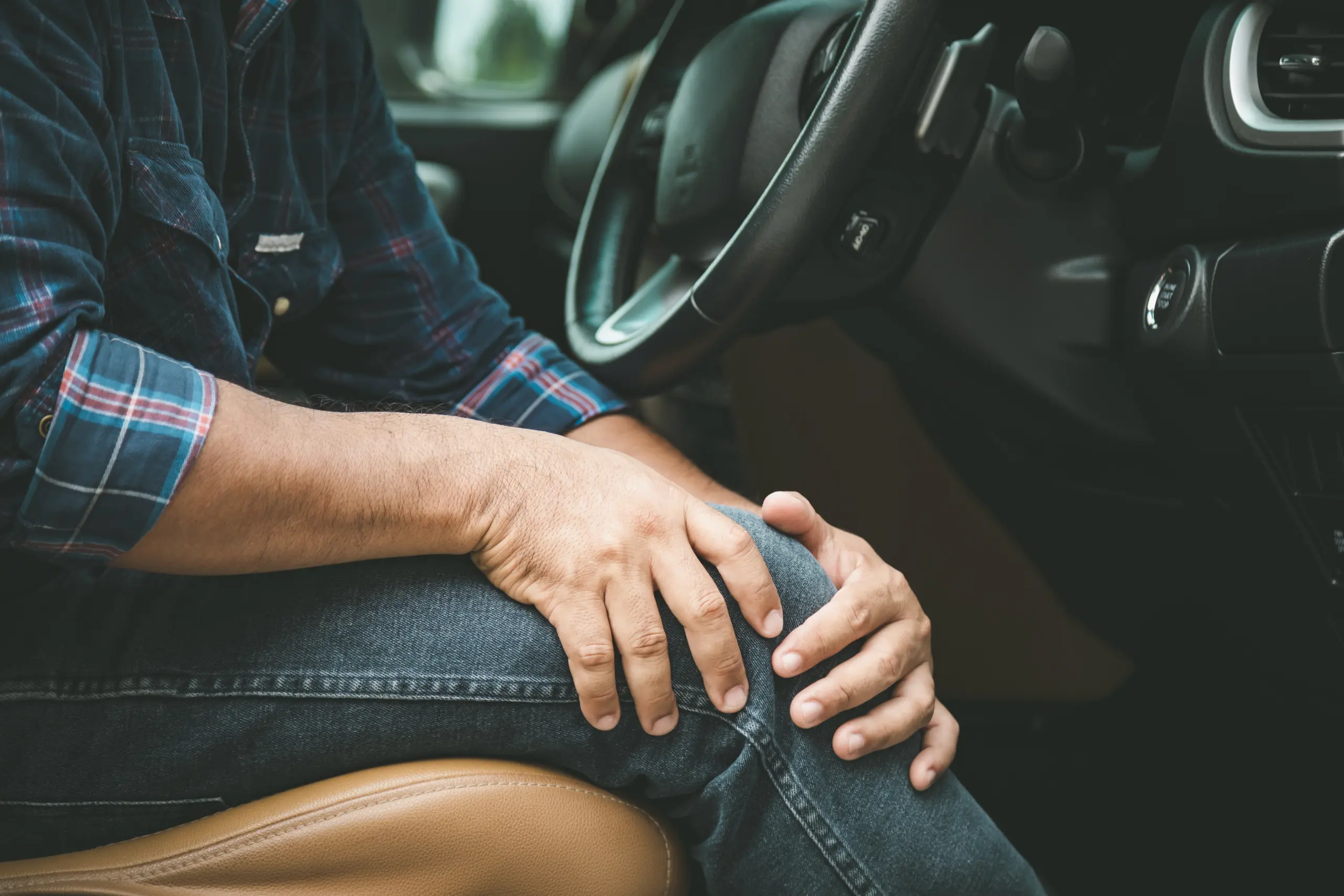 Driver holding a knee inside a car