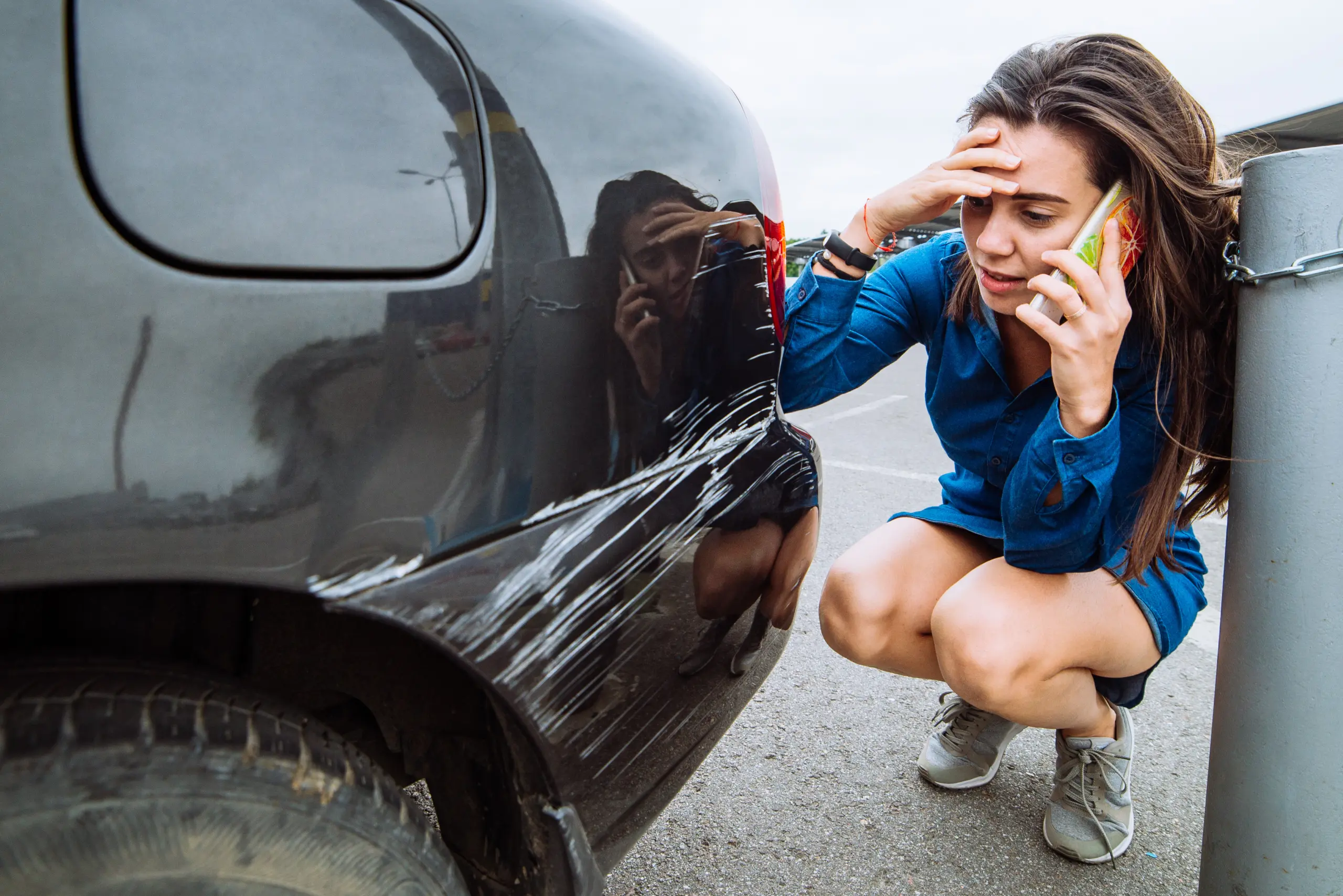 Woman calling for help beside a scratched vehicle after a collision